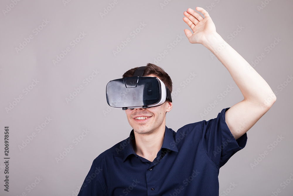 Excited man experiencing virtual reality for the firts time. He is wearing a VR headset. Gray background. Studio photo Excited man experiencing virtual reality for the firts time. He is wearing a VR headset. Gray background. Studio photo