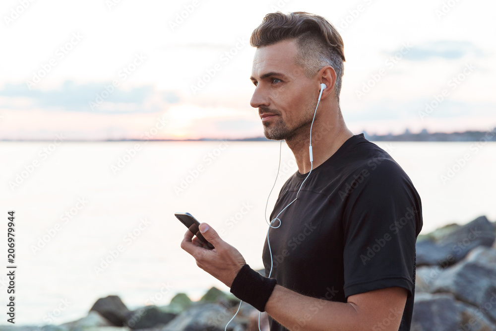 Portrait of a fit sportsman listening to music with earphones