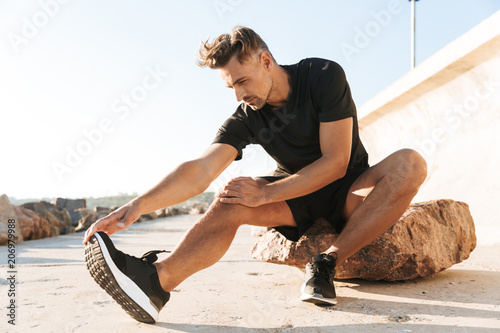 Portrait of a charming sportsman doing stretching exercises