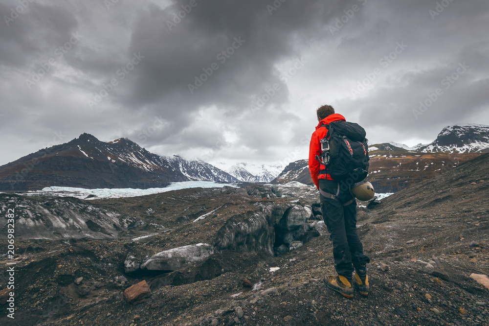 Hiking adventure travel man watching glacier in Iceland.
