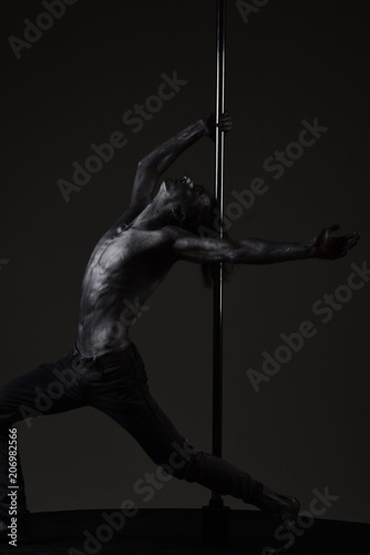 Plasticity concept. Guy, athlete, sportsman puts hand on metallic pole