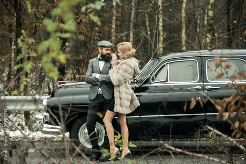 Escort of girl by security. Travel and business trip or hitch hiking. Bearded man and sexy woman in fur coat. Retro collection car and auto repair by mechanic driver. Couple in love on romantic date.