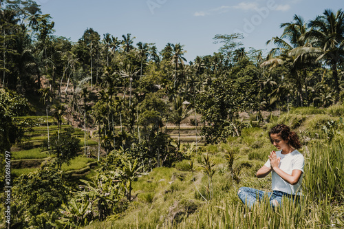 Young happy woman enjoying and meditating with the lovely view of the rice terrace in Bali  Indonesia. Sunny  relaxed day in Tegalalang. Travel photograph. Lifestyle.
