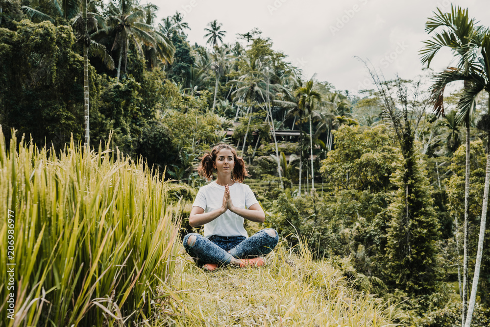 Young happy woman enjoying and meditating with the lovely view of the rice terrace in Bali, Indonesia. Sunny, relaxed day in Tegalalang. Travel photograph. Lifestyle.