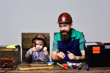 Fatherhood, repair, assistance concept - concentrated boy with father repairing together. Dad teaching little son to use tools. Cute boy exploring new stuff. Kid with screwdriver playing in craftsman.