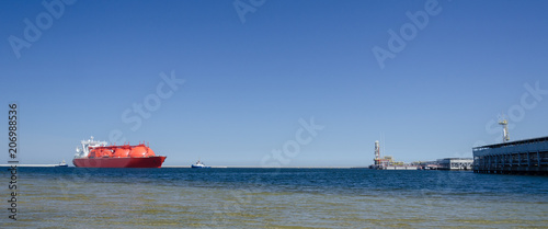 LNG TANKER - The red ship enters port with assurance of tugs
