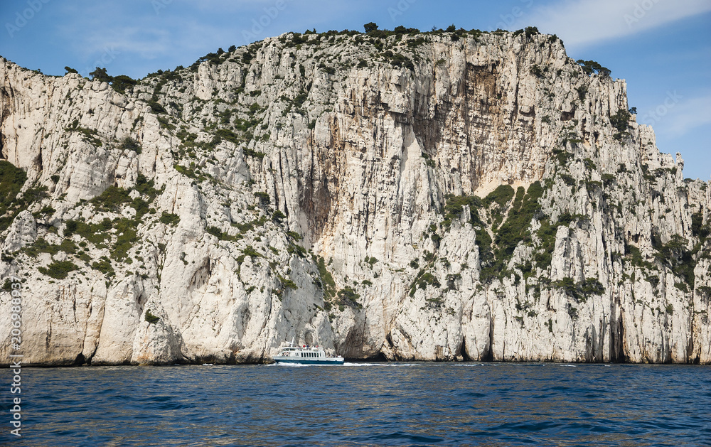 The famous Calanques national park of Cassis (near Marseilles in Provence, France) - blue water, white rocks and tourist ship.