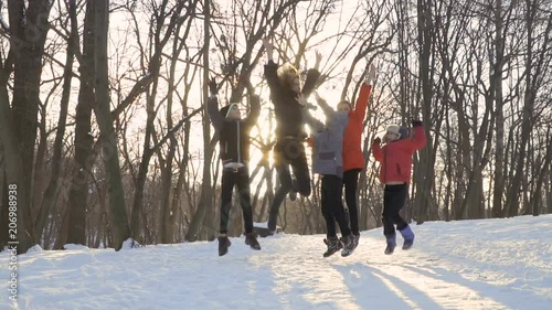 Mother with sons jump in slow motion at the background of winter park photo