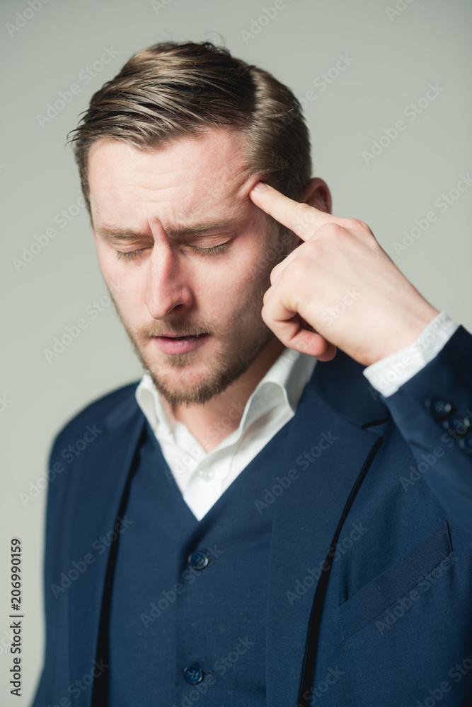 Young intellectual with closed eyes dealing with problem Portrait of tired businessman pressing his pointing finger on head isolated on gray background Young intellectual with closed eyes dealing with problem Portrait of tired businessman pressing his pointing finger on head isolated on gray background