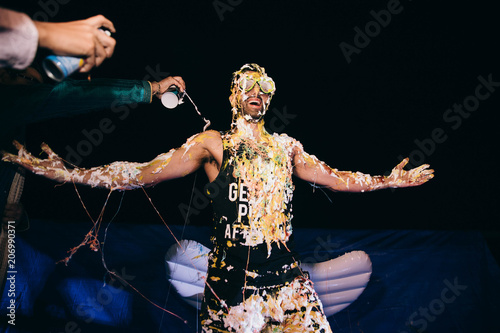 People cover Hindu groom with different sauces on a pre-wedding party photo