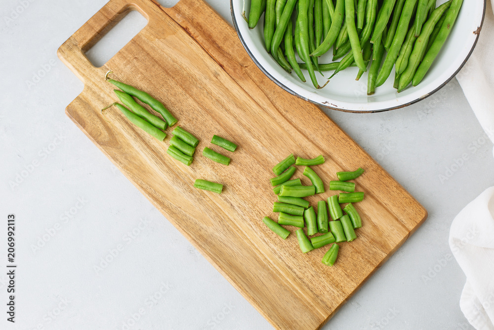 Freshly Picked Green Beans in a White Bowl, Some Cut on Cutting Board, all on Gray Background