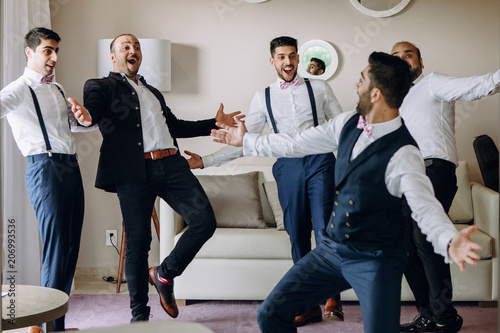 Groom and groomsmen have fun dancing in the hotel room photo