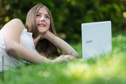 Young dark blonde girl studying in a park with a laptop