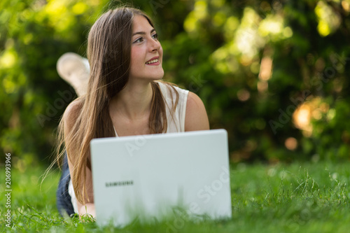 Young dark blonde girl studying in a park with a laptop