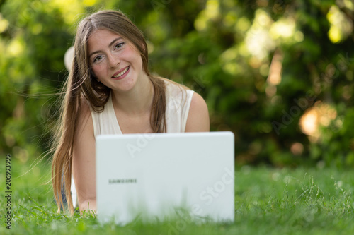 Young dark blonde girl studying in a park with a laptop