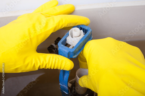 Fotografie Plumber repairing toilet cistern at water closet, closeup