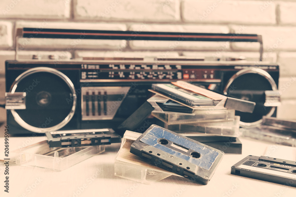 Obraz premium Vintage audio cassette on wooden background. Collection of a various retro audio tapes and tape recorder