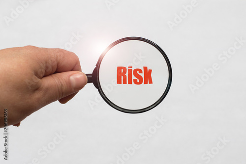 Fotografi magnifying glass in hand and a risk word on the white background