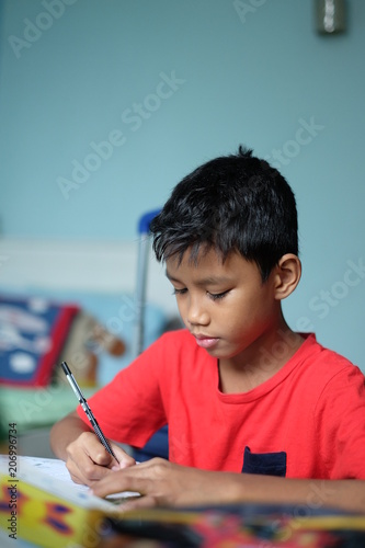 A boy writing something on the book