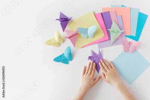 Children's hands do origami from colored paper on white background. lesson of origami
