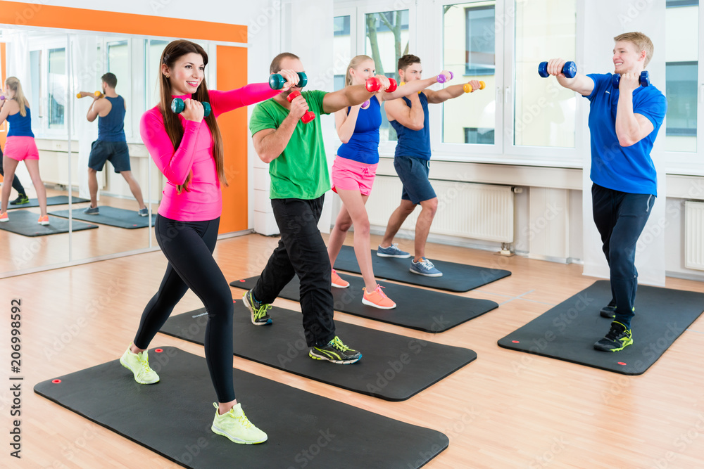 Obraz premium Men and woman doing workout with small weights in fitness studio gym