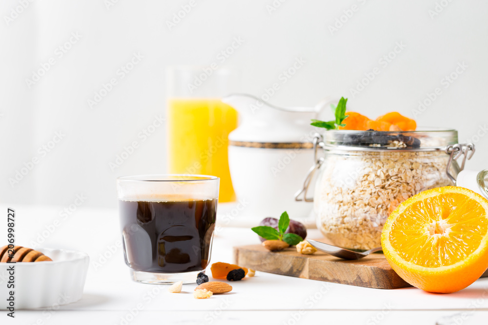 Healthy breakfast in glass mason jar with oat flakes, granola, milk, dry fruits and nuts, dates, honey, orange juice, eggs for morning fitness on wooden board platter on white background isolated Healthy breakfast in glass mason jar with oat flakes, granola, milk, dry fruits and nuts, dates, honey, orange juice, eggs for morning fitness on wooden board platter on white background isolated