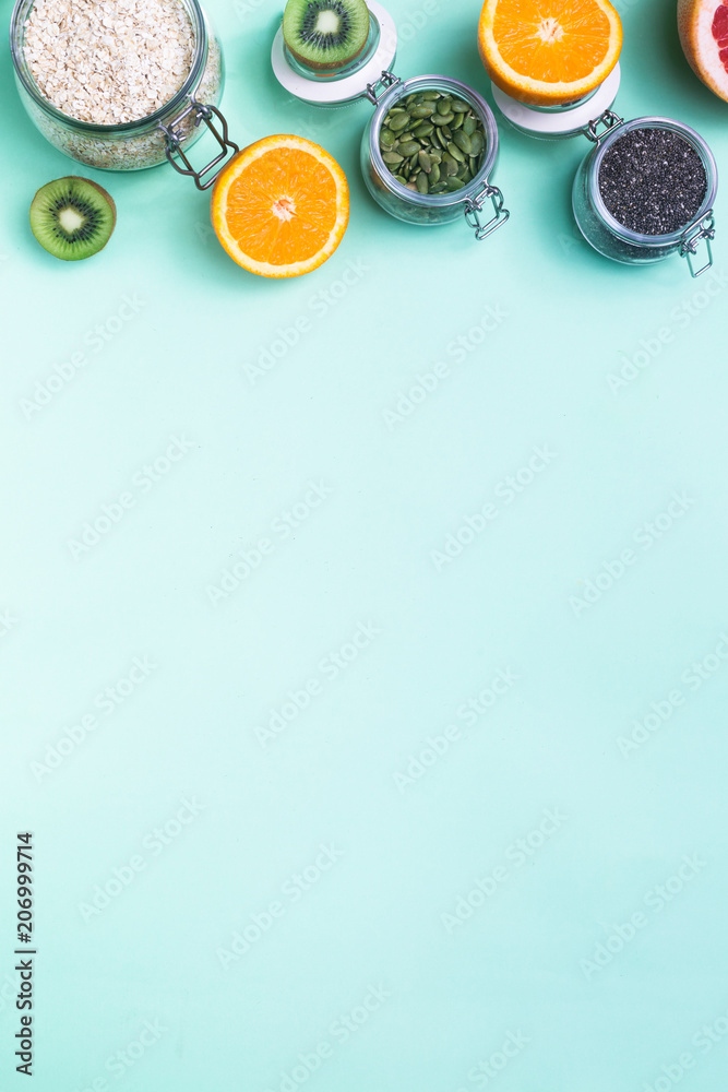 Food for fitness, healthy lifestyle frame flat lay with fresh fat burning fruits orange and grapefruits slices, complex carbohydrates, detox water bottle, pink hand weights, light green background
