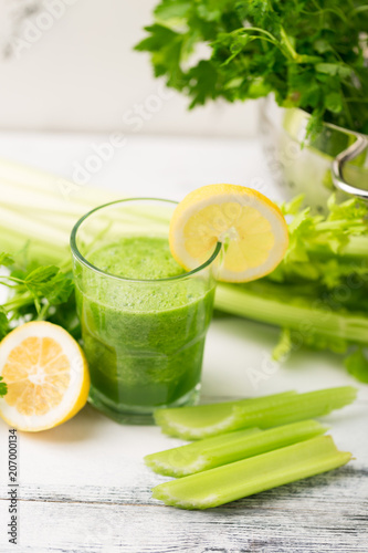 Green cocktail smoothie parsley celery lemon lime slices, healthy drink ingredients, glass of beverage on white wooden table, detox diet clean eating, with vegetables on table