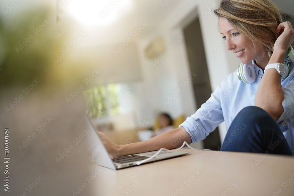 Blond woman at home connected with laptop