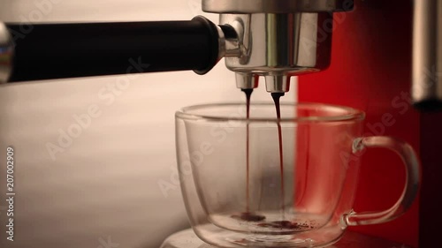 Сoffee is poured from a coffee machine into a glass cup