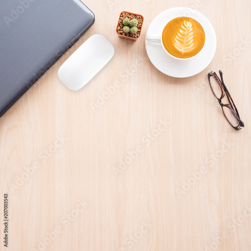 Office table with laptop, mouse, coffee cup on table background.