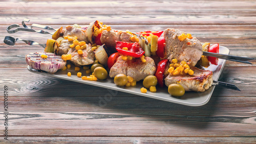 Chicken kebab with vegetables on a wooden table. Banner