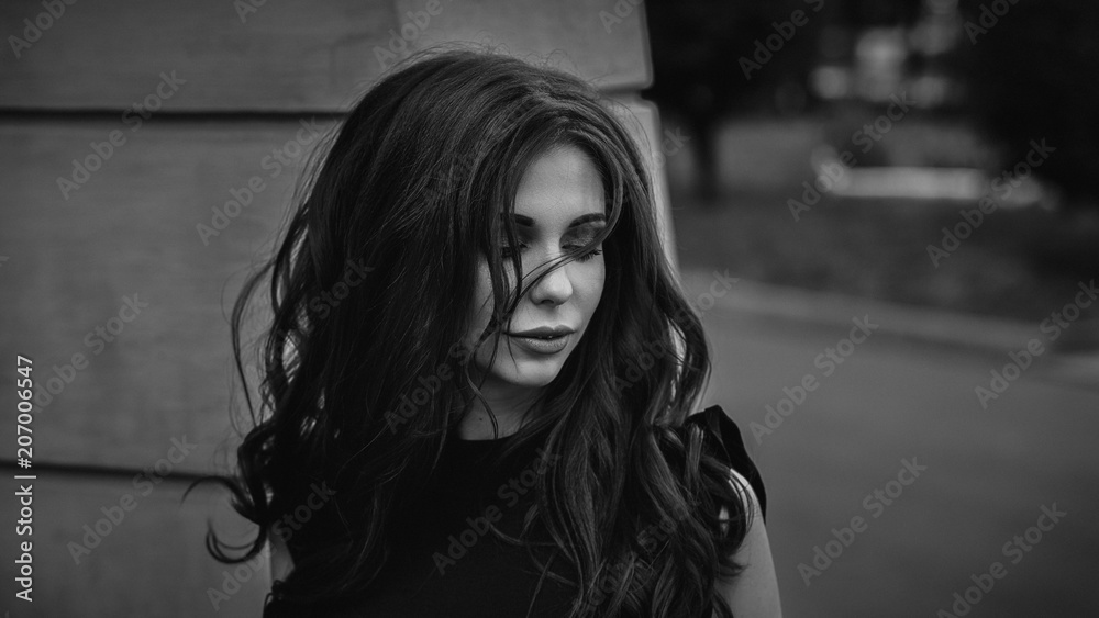 Gothic young brunette woman outdoors with wind in hair, shallow depth of field