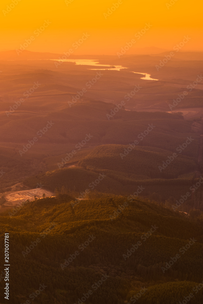 Orange gold sunrise light creeping over hills, valleys and rivers at Gods Window in Mpumalanga South Africa