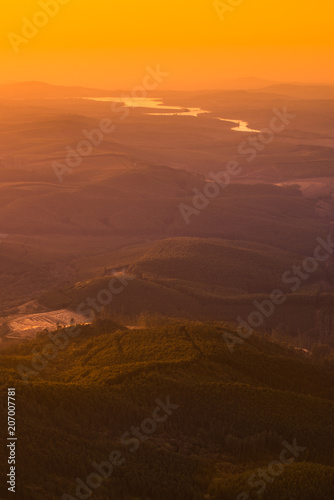 Orange gold sunrise light creeping over hills  valleys and rivers at Gods Window in Mpumalanga South Africa