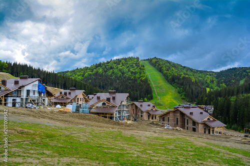 Construction of cottages in the mountains against the backdrop of the ski slope.