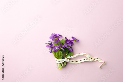 violet flowers in bouquet on pink background, flat lay. Spring, summer romantic minimal concept