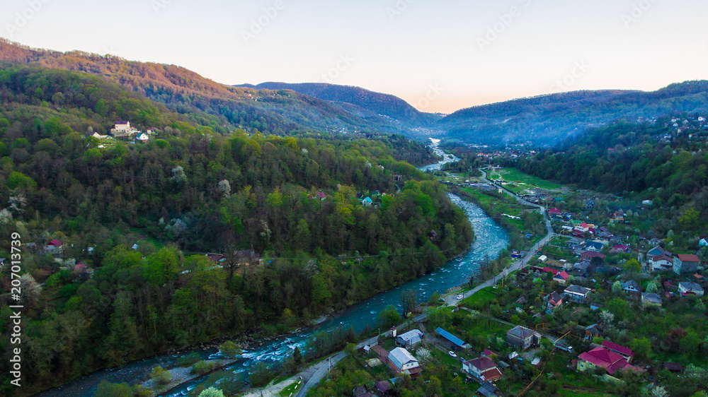 Drone view of mountains and Plastunka village in the valley of the Sochi river in spring evening, Sochi, Russia
