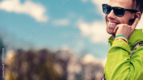 Smiling happy tourist talking on phone with bluetooth headset device photo