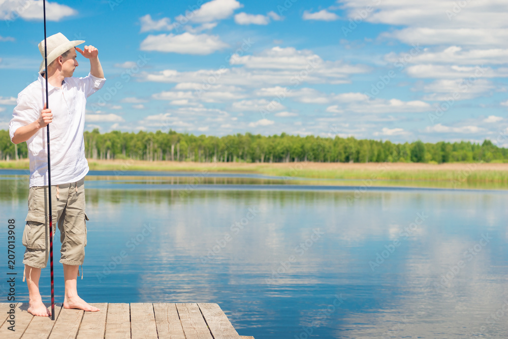 Fototapeta premium portrait of a fisherman on a pier looking away into the lake