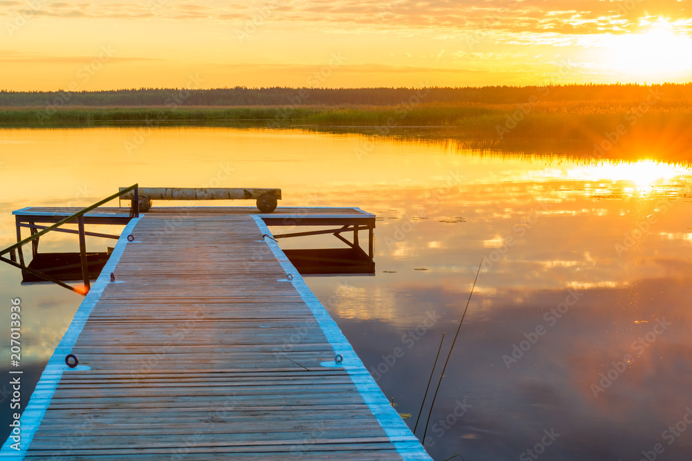 Naklejka premium horizontal picture of a beautiful landscape - a long wooden pier and the setting sun over a picturesque lake