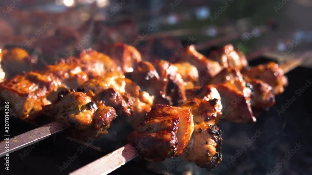 Appetizing delicious fried pieces of meat on skewers are roasted on a large grill in the open air. The chef prepares a barbecue. slow motion