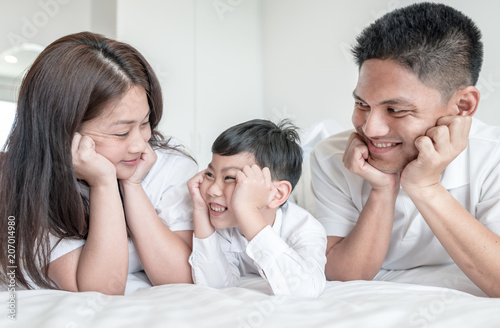 à¹‰portrait happy family mom dad and son  smiling in bed room. look at each other. © saksit