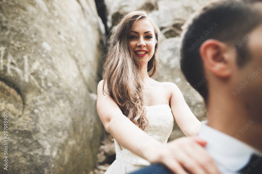 Happy wedding couple kissing and hugging near a high cliff Happy wedding couple kissing and hugging near a high cliff
