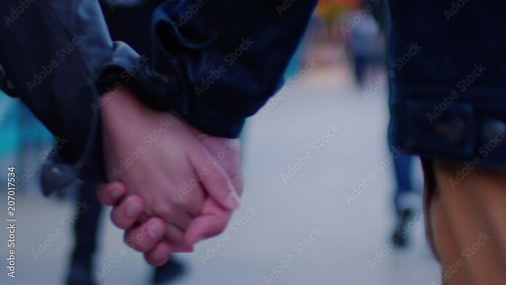 Closeup Of Couple Holding Hands As They Walk Down Busy Sidewalk In Venice Beach, After Sunset (Slow Motion) Closeup Of Couple Holding Hands As They Walk Down Busy Sidewalk In Venice Beach, After Sunset (Slow Motion)