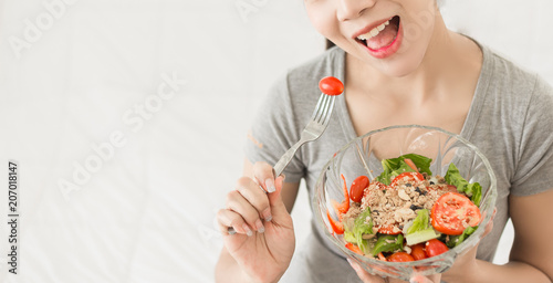 Enjoyed Asian woman eating vegetable salad.