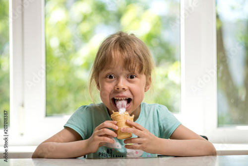 Little girl eating ice cream while sitting at a table  free space.