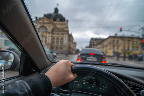 first-person view. man driving car by city streets. urban traffic