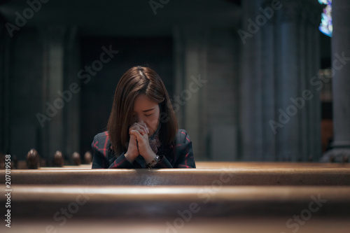 A Christian girl is sitting and praying with broken heart in the church.