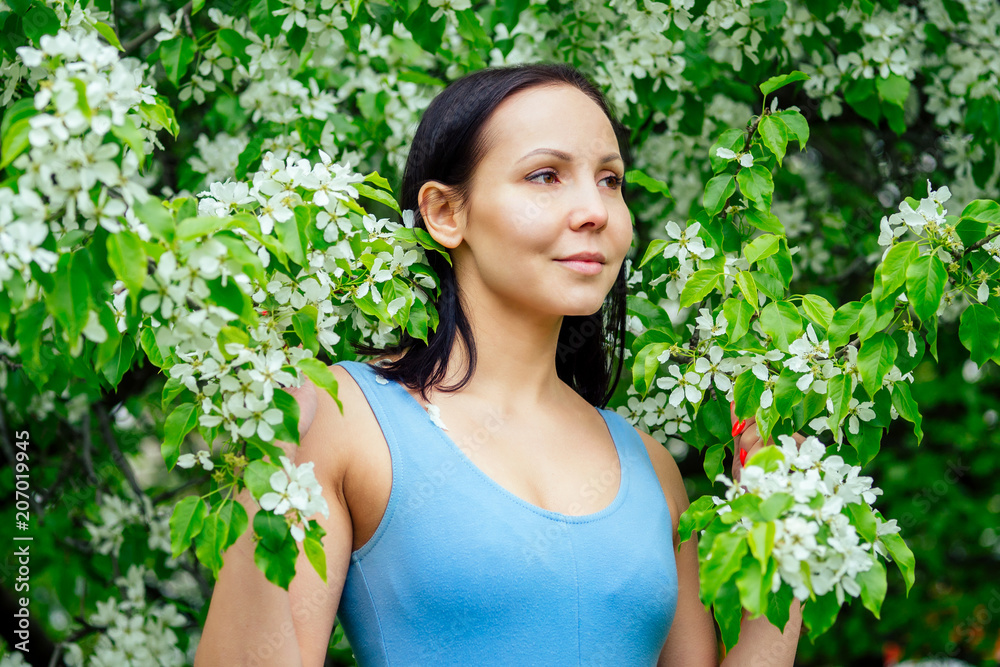 beautiful brunette woman in a sporty blue suit against a background of flowering spring trees beautiful brunette woman in a sporty blue suit against a background of flowering spring trees